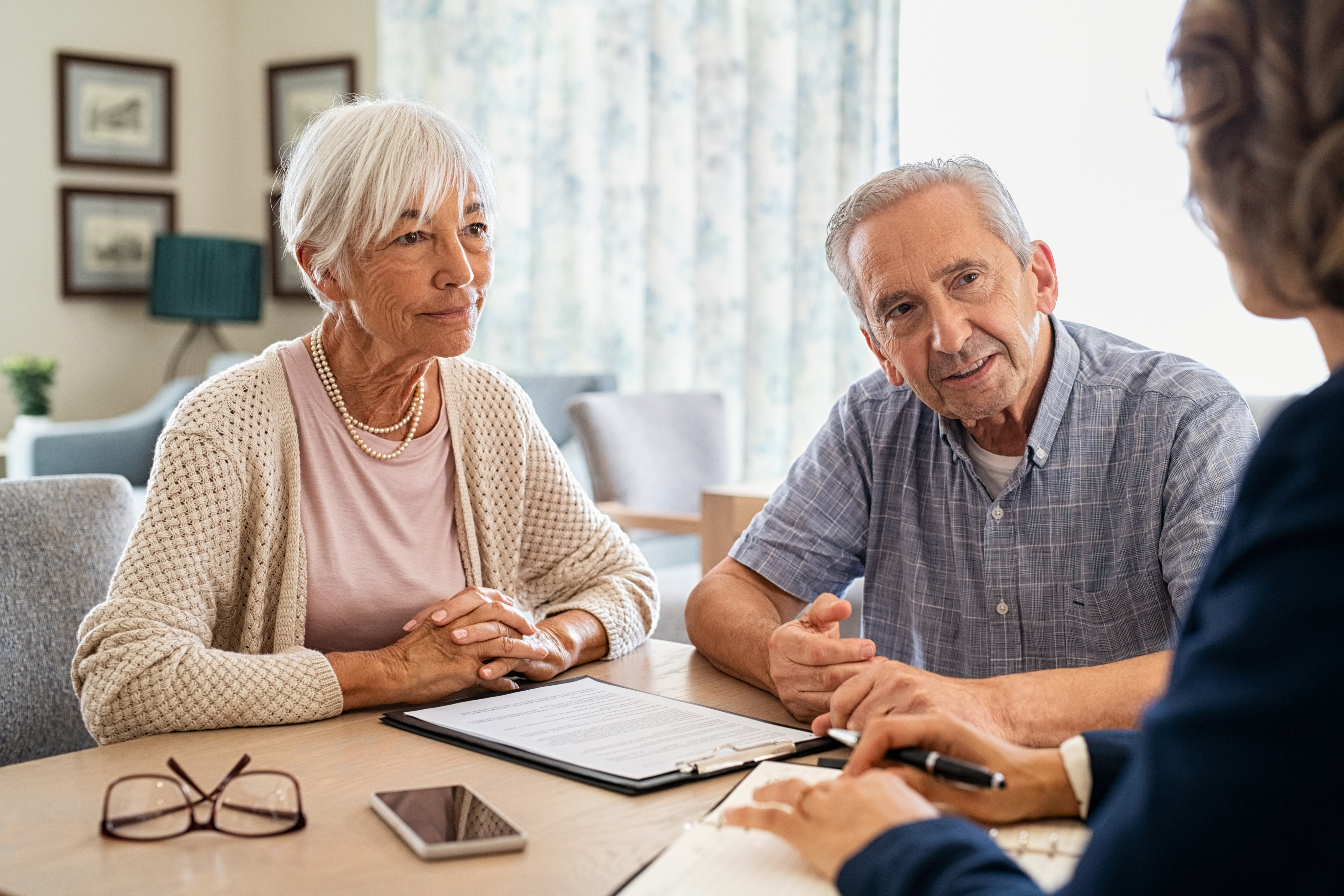 A professional advisor offers support and guidance to an elderly couple at their table, representing personalised in-home care planning and services navigation.